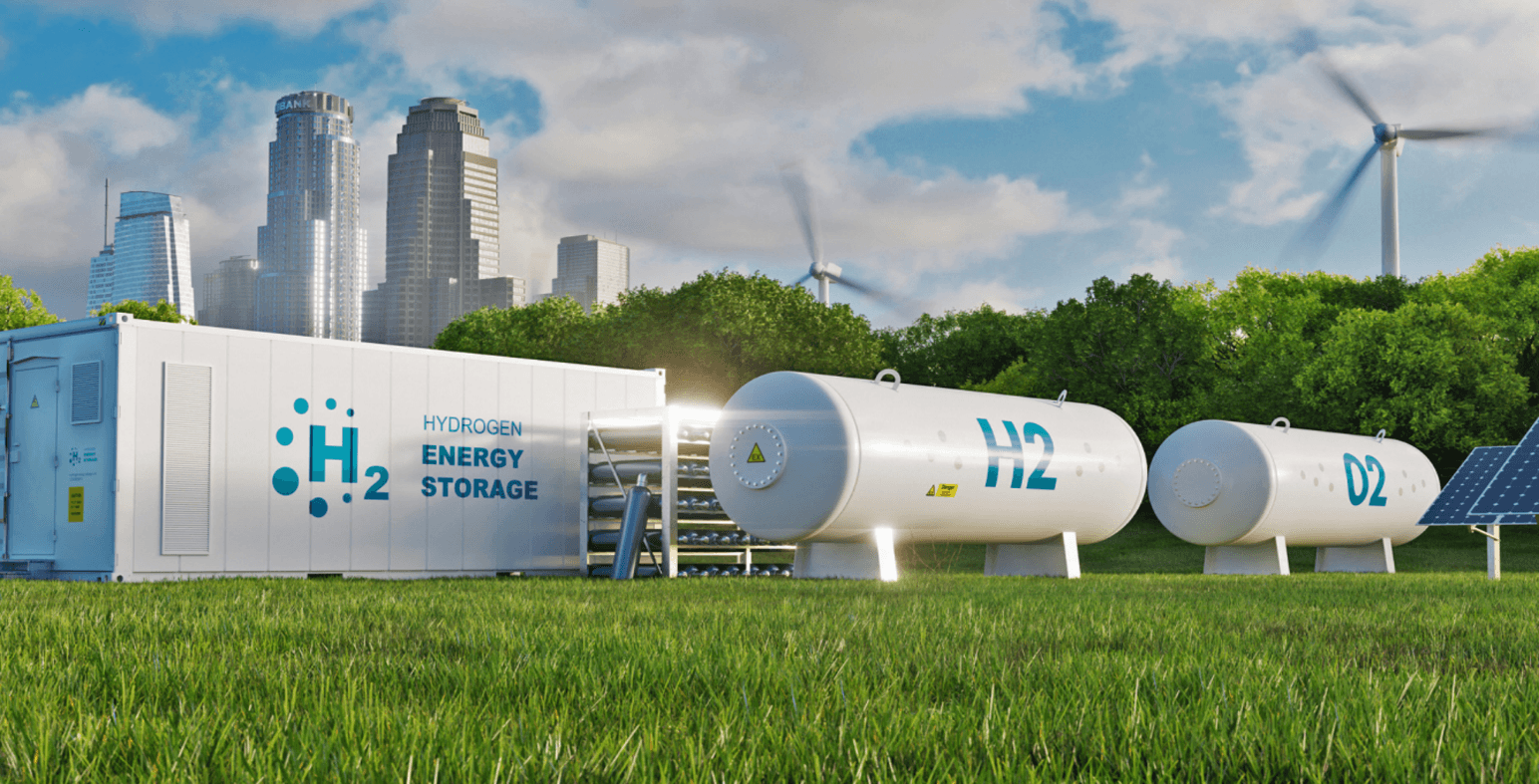 A hydrogen energy storage unit and white storage tanks on grass, with wind turbines and a city skyline behind